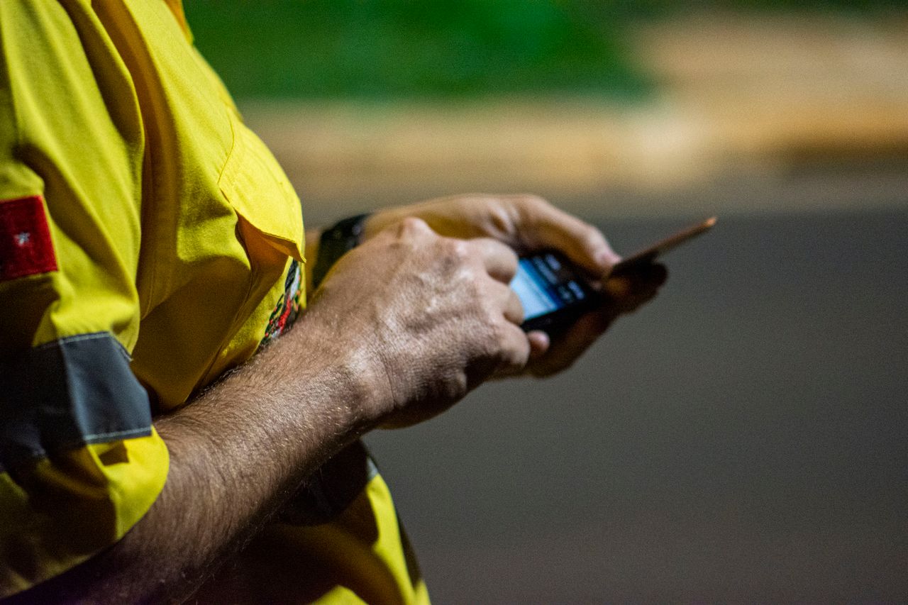Arbeidere jobber på mobil på plassen